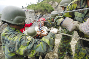 13日，臺灣高雄縣六龜鄉(xiāng)新開村有20多戶遭泥石流淹沒。圖為軍人正陸續(xù)將生還者救出。