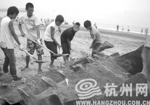 大連市金石灘國賓浴場，工作人員將帶有油污的沙子清理掉。