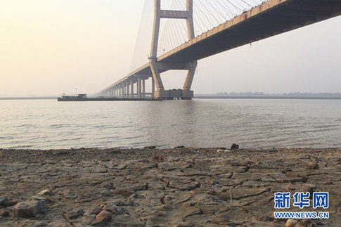 這是12月10日在江西省湖口縣境內(nèi)的鄱陽(yáng)湖大橋附近拍攝的已經(jīng)干涸開(kāi)裂的湖灘。