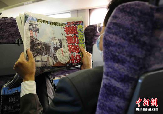 3月17日下午，在一列前往東京的新干線列車(chē)上，一名日本人在閱讀關(guān)于福島核電站三號(hào)機(jī)組最新?tīng)顩r的報(bào)道。中新社發(fā) 侯宇 攝