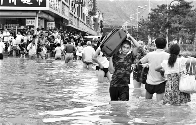 昨日，一名消防戰(zhàn)士在秦皇島市山海關(guān)火車站站前廣場涉水幫助旅客運送行李。 新華社發(fā)
