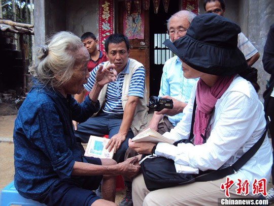 日本“海南島近代史研究會(huì)”創(chuàng)始人佐藤正人第22次到海南島調(diào)查日本侵瓊史。圖為在保亭黎族苗族自治縣南林鄉(xiāng)羅葵村，金靜美握著86歲老人林亞金的手。中新社發(fā) 張茜翼 攝