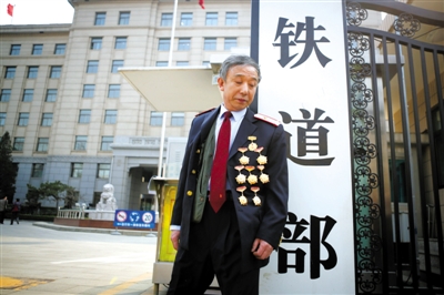 3月14日，鐵道部大門口，一位胸前掛著多枚勛章的鐵道部老職工與鐵道部牌子合影。 新京報(bào)記者 侯少卿 攝